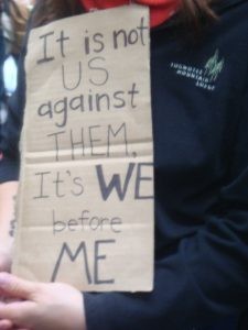 Figure 2.11 A person holding a cardboard sign that reads: It is not US against THEM, It's WE before ME.