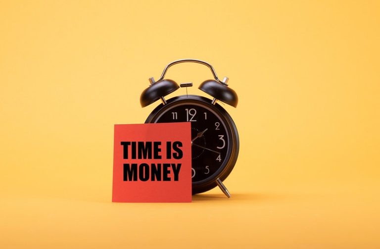 A black alarm clock on a yellow background, partially covered by a red sticky note reading TIME IS MONEY.
