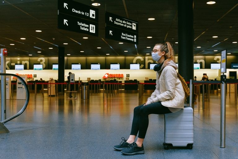 A woman sits on her luggage at the airport