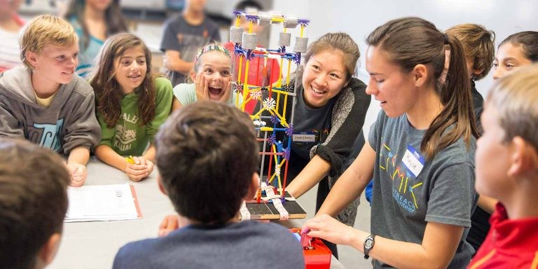Excited students watching an instructor demonstrate an interactive science project