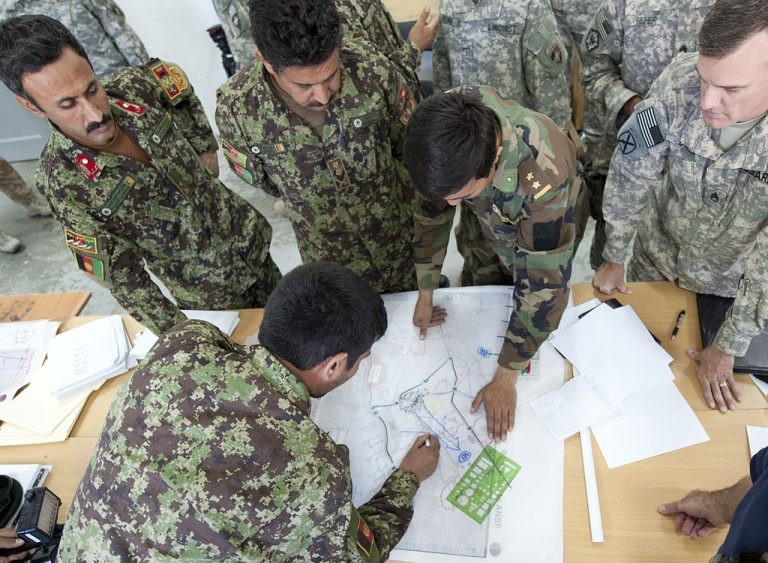 People in military uniforms discussing strategy around a table.