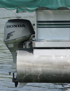 Side view of a Honda motor attached to a pontoon boat in the water