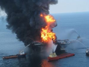 The oil rig Deepwater Horizon on fire in the Gulf of Mexico. Five boats surround it spewing water to put out the fire