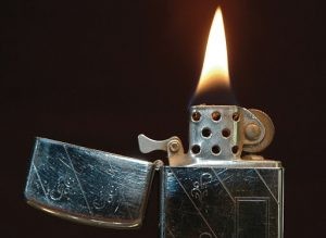 A lit Zippo lighter from 1968 sits in front of a dark background