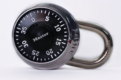 Round black Master Lock with a silver metal shackle. Numbers are visible on the dial.