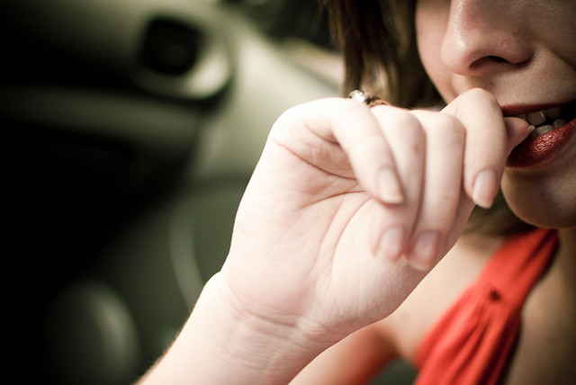 Close-up of a woman biting her fingernails, suggesting anxiety or nervousness.