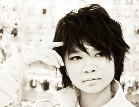 Sepia-toned portrait of a person touching their temple with a thoughtful, reflective expression.