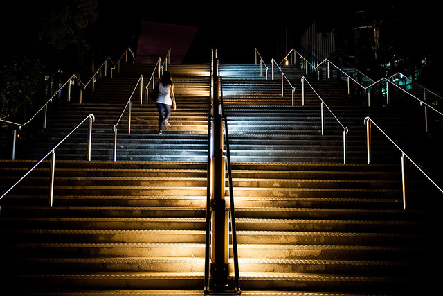 A wide flight of outdoor stairs illuminated by lights at night.