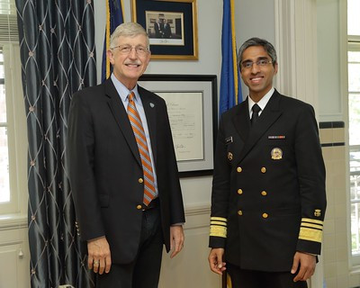 Francis Collins and Vivek Murthy standing side by side in formal attire indoors in front of framed artwork.